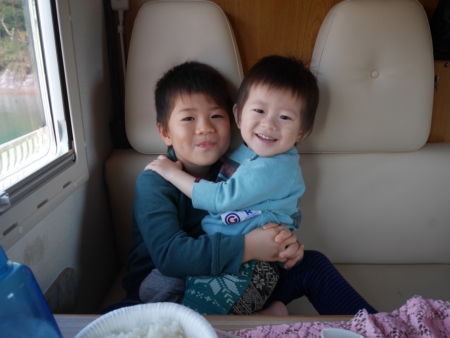 キャンピングカーの車内で笑顔を見せる兄弟